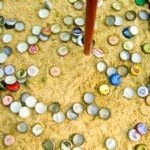 bottle caps in sand - photo by: ryan sterritt